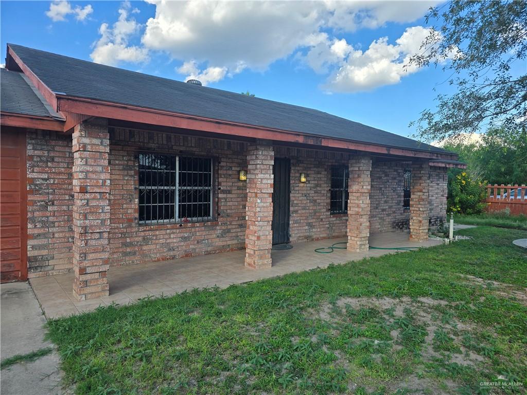 Back of property featuring brick siding, a patio, and a lawn