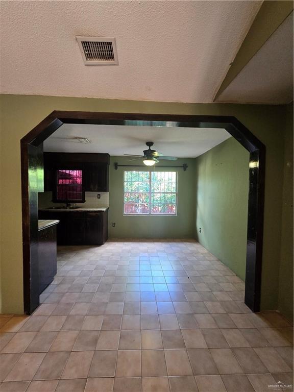 519 East 3rd Street Sullivan City, TX 78595 - Photo 5 of 12 Unfurnished living room featuring arched walkways, a textured ceiling, ceiling fan, and light tile patterned floors