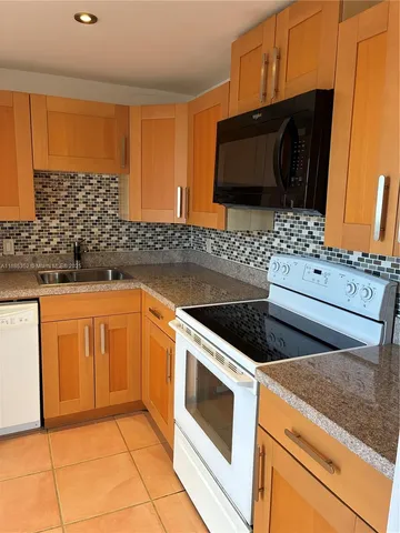 a kitchen with stainless steel appliances kitchen island granite countertop a stove a sink and a microwave