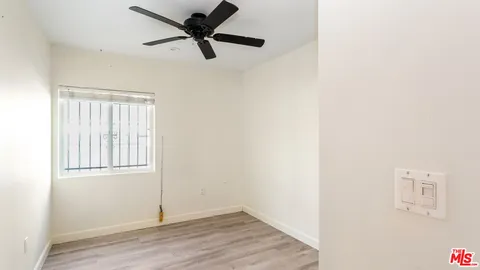 an empty room with wooden floor fan and windows