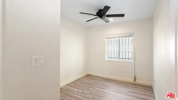 an empty room with a window and a ceiling fan