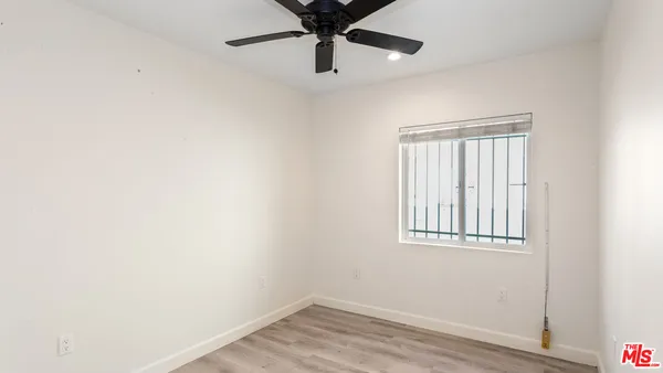 an empty room with wooden floor ceiling fan and windows