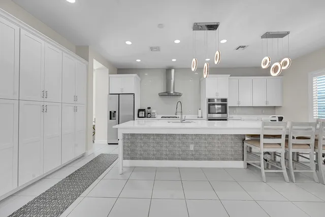 a kitchen with kitchen island granite countertop a sink cabinets stainless steel appliances and a chandelier