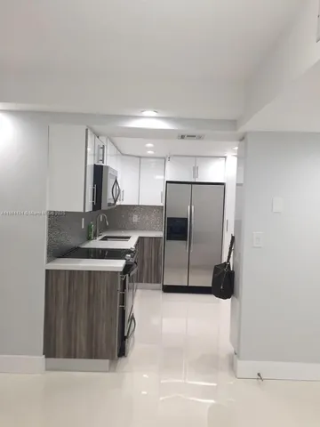 a kitchen with stainless steel appliances a refrigerator a sink a stove and white cabinets