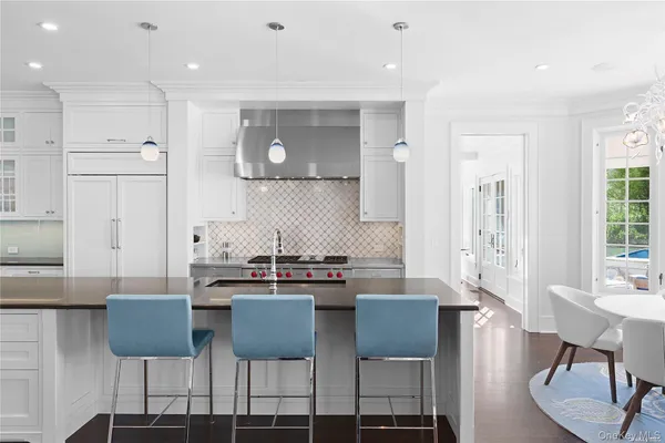 a kitchen with stainless steel appliances kitchen island granite countertop a dining table chairs and a refrigerator