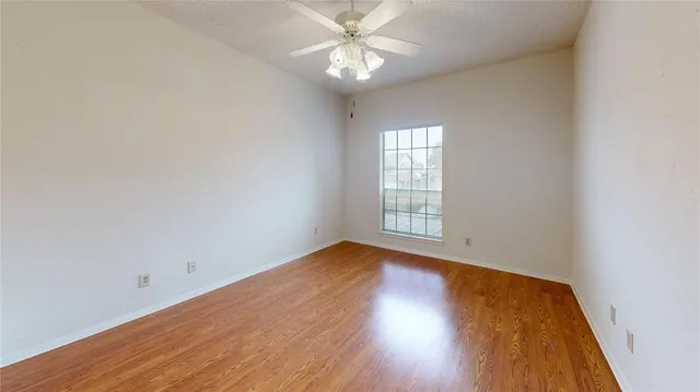 an empty room with wooden floor closet and windows