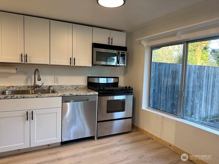10341 184th Avenue Southwest Rochester, WA 98579 - Photo 26 of 36 a kitchen with granite countertop a stove a sink and a microwave