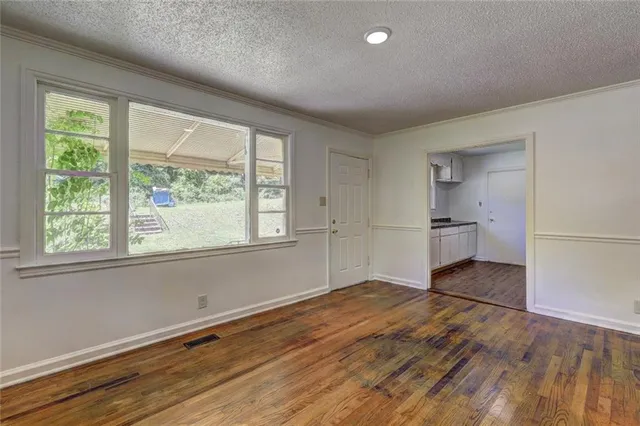 a view of empty room with a kitchen and wooden floor