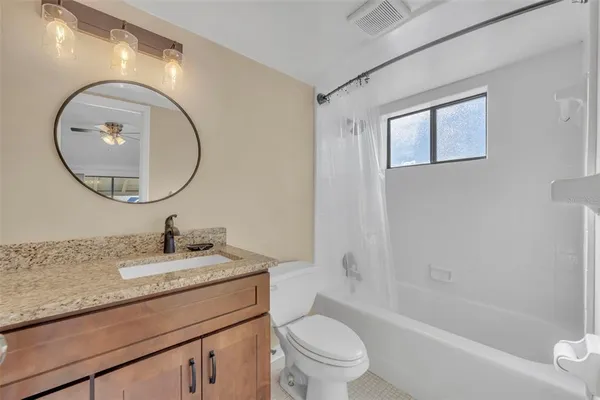 a bathroom with a granite countertop toilet a sink and a mirror