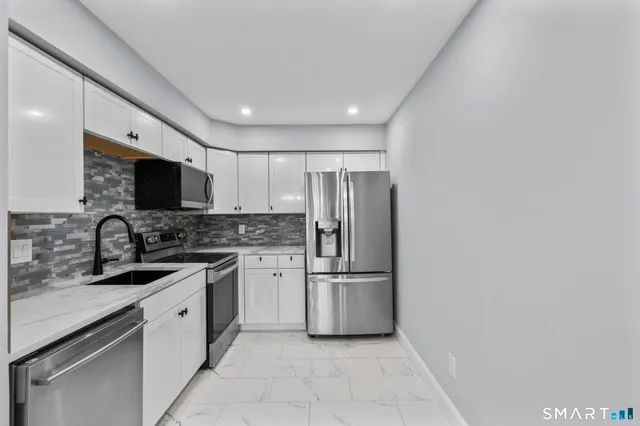 a kitchen with white cabinets and stainless steel appliances