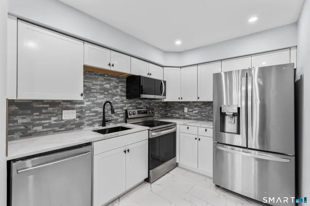 a kitchen with stainless steel appliances granite countertop a refrigerator sink and microwave