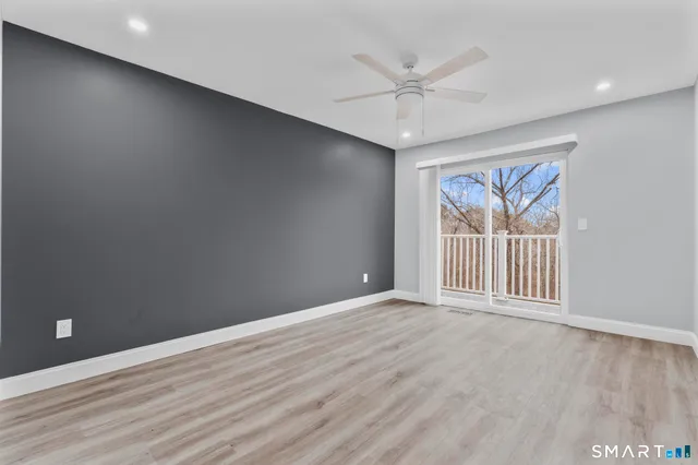 an empty room with wooden floor fan and windows