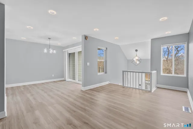 a view of an empty room with wooden floor and windows