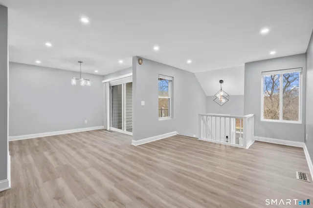 a view of an empty room with wooden floor and windows