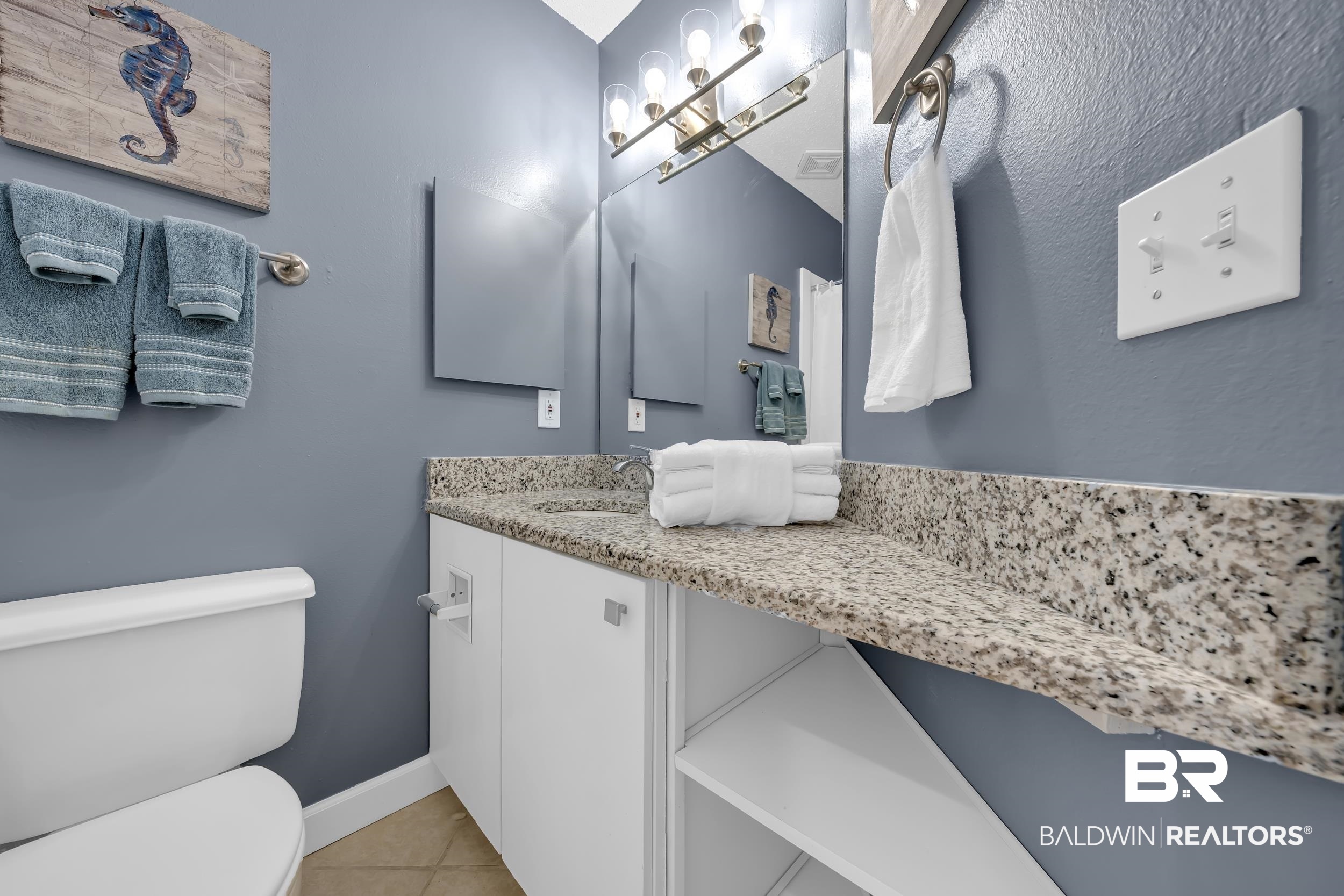27222 Gulf Road, Unit 33 Orange Beach, AL 36561 - Photo 25 of 29 Bathroom vanity featuring a speckled countertop, white cabinetry, and an integrated sink with a chrome faucet