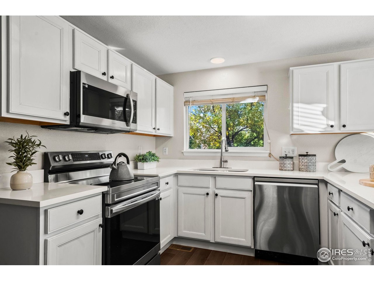 2529 Azalea Way Erie, CO 80516 - Photo 10 of 32 a kitchen with stainless steel appliances granite countertop white cabinets a sink a stove a microwave a sink and dishwasher with wooden floor
