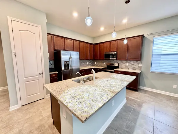a kitchen with stainless steel appliances granite countertop a refrigerator oven a sink dishwasher and wooden cabinets with a granite countertops