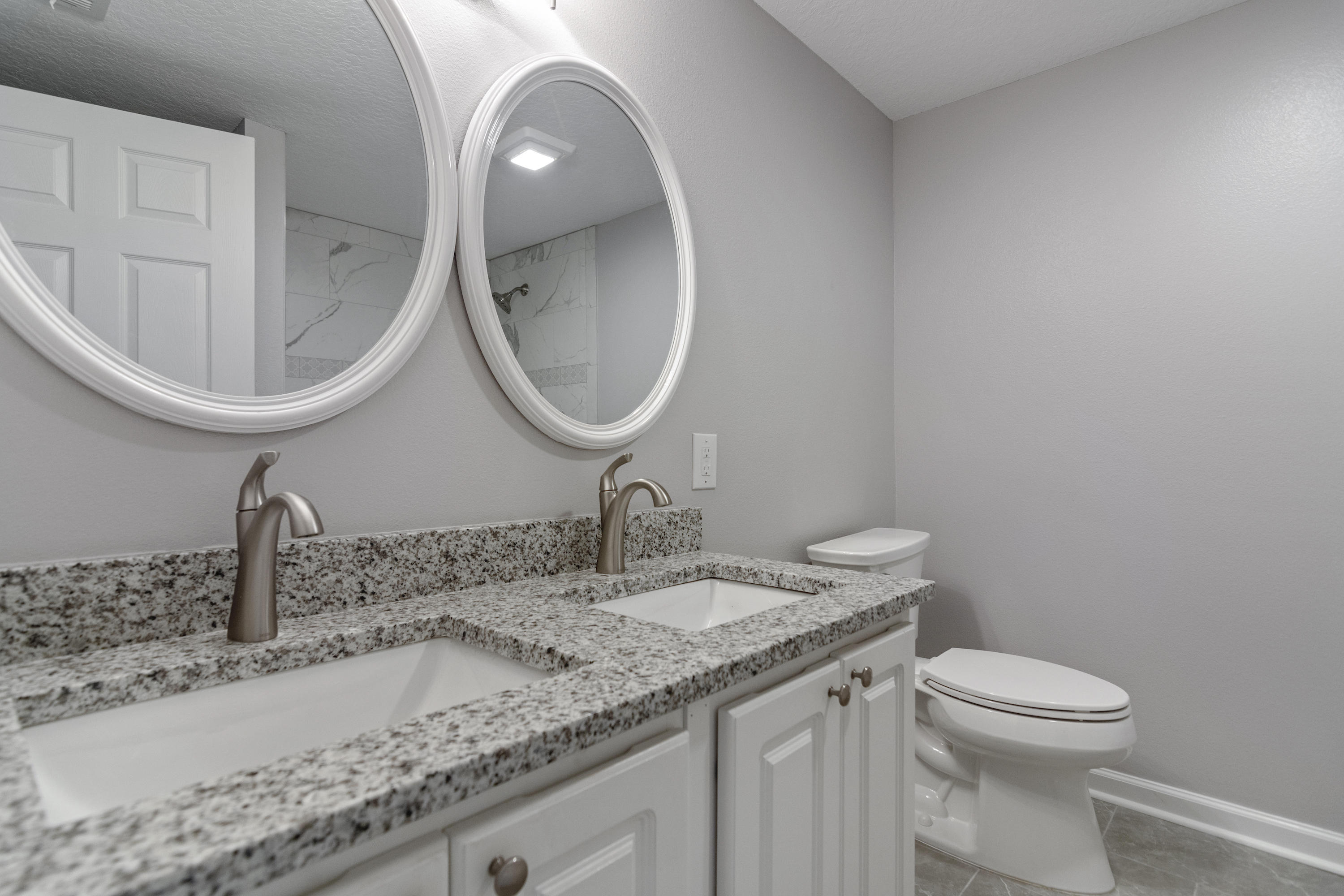 3032 Adams Road Crestview, FL 32536 - Photo 31 of 41 a bathroom with a granite countertop toilet a sink and mirror