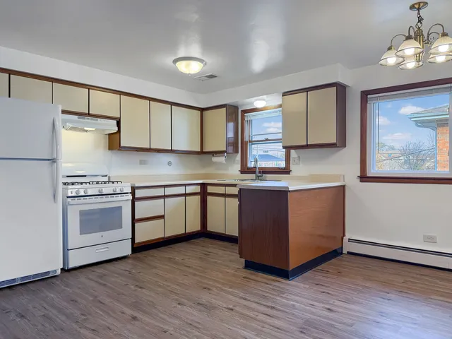a kitchen with kitchen island granite countertop wooden floors and white stainless steel appliances