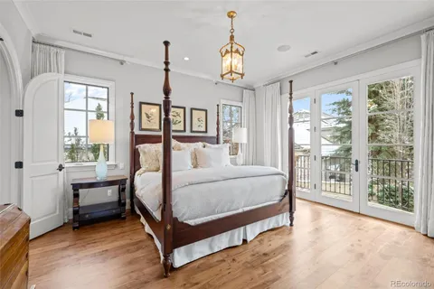 a bedroom with a large bed and a chandelier next to a window