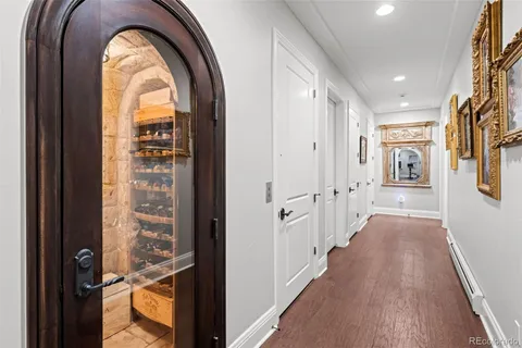 a view of a hallway with wooden floor and a bathroom