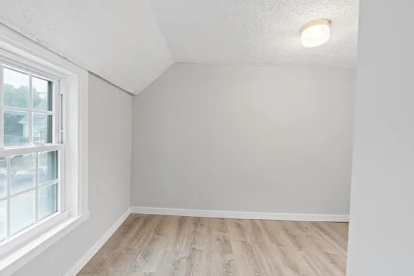 a view of an empty room with a window and wooden floor