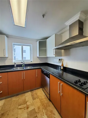 a kitchen with stainless steel appliances kitchen island granite countertop a refrigerator and a sink