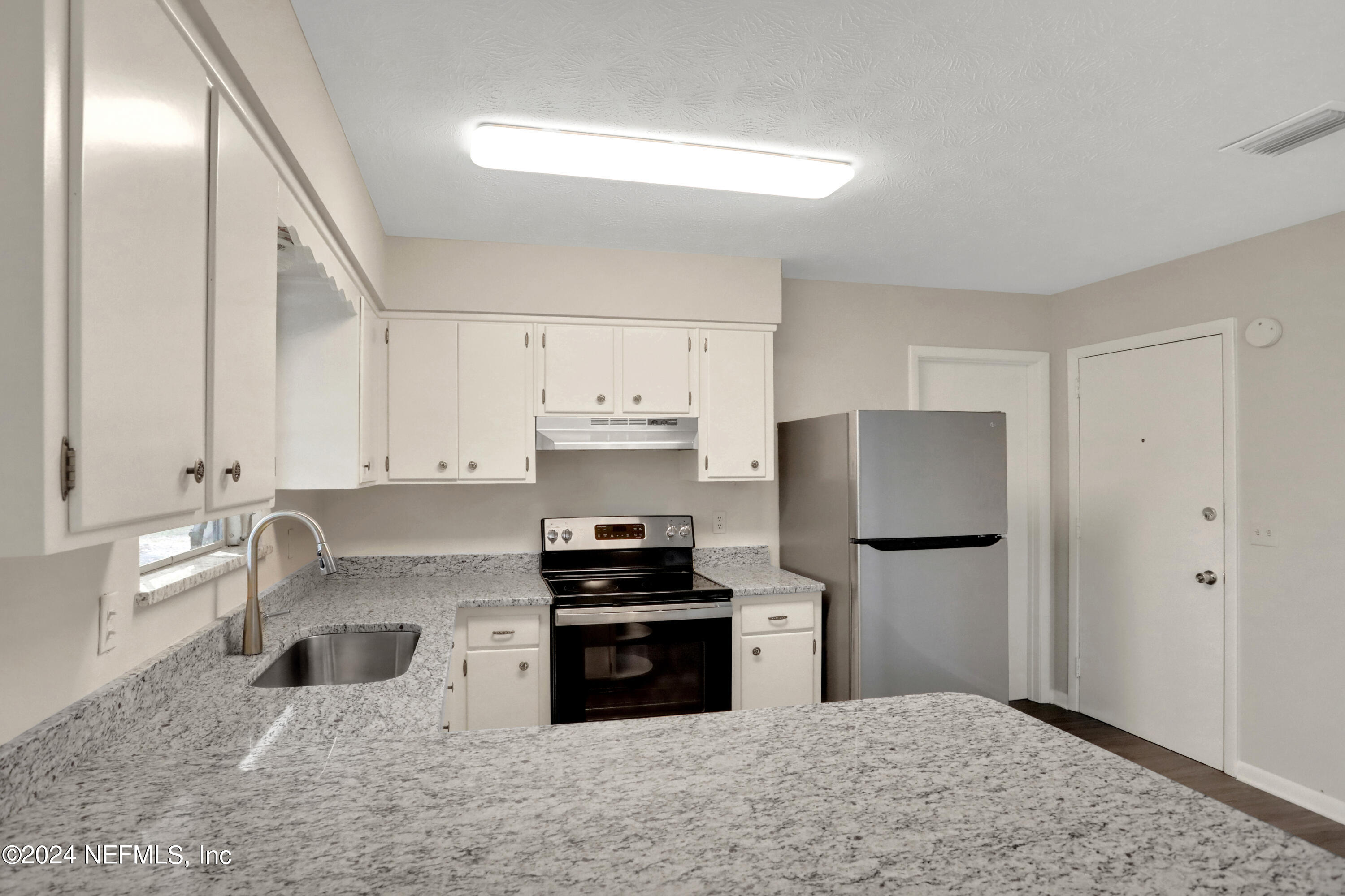 3211 Victoria Park Road Jacksonville, FL 32216 - Photo 9 of 25 a kitchen with granite countertop a refrigerator and a stove top oven