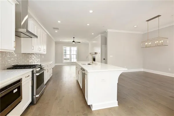 a large kitchen with stainless steel appliances granite countertop a lot of counter space and wooden floors