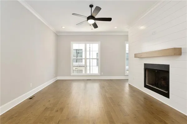 a view of empty room with wooden floor fireplace and a window