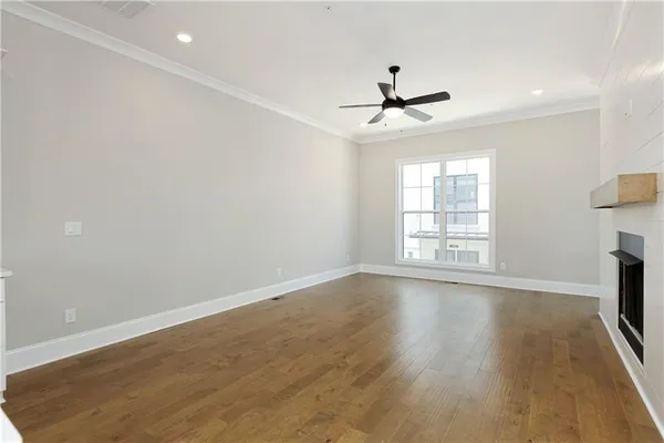 an empty room with wooden floor ceiling fan and windows