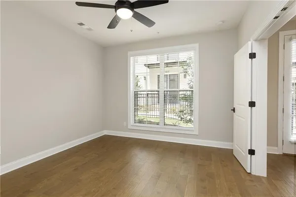 an empty room with wooden floor fan and windows