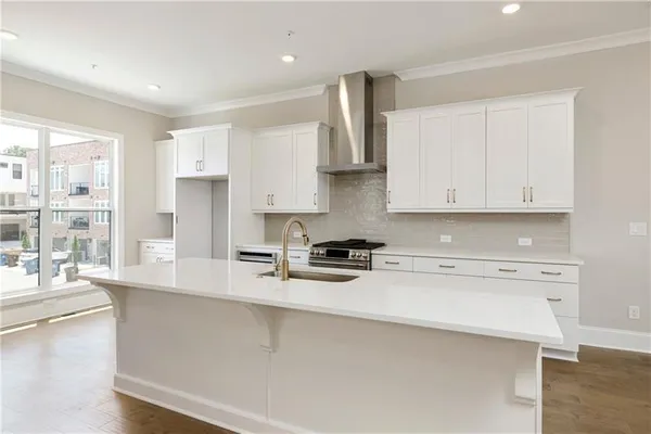 a kitchen with stainless steel appliances a sink a stove a refrigerator cabinets and a window