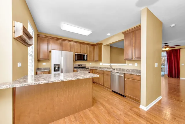 a large kitchen with stainless steel appliances a large counter top a stove a refrigerator and a sink