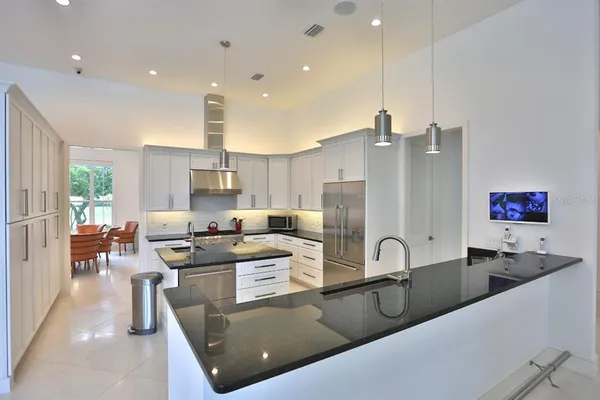 a large kitchen with stainless steel appliances granite countertop a sink a stove and a refrigerator