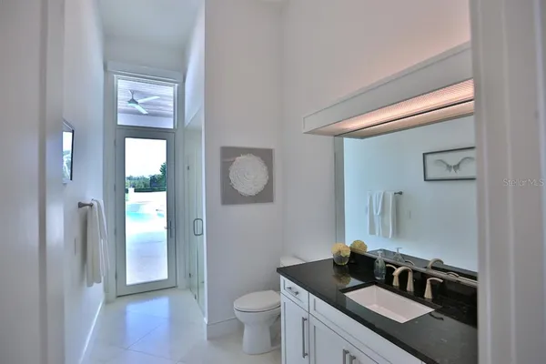 a bathroom with a granite countertop sink vanity mirror and toilet