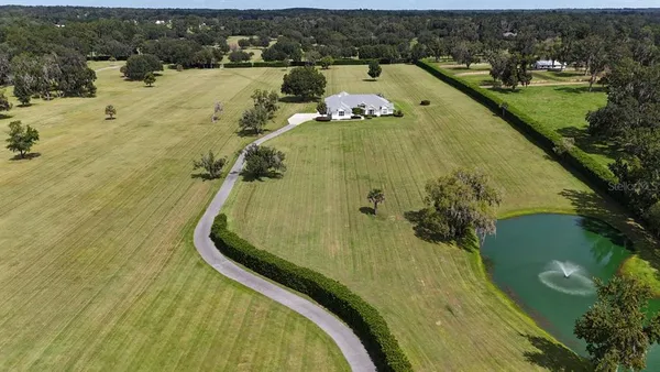an aerial view of a house with a garden and lake view