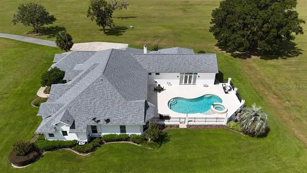 an aerial view of a house with garden space and a swimming pool