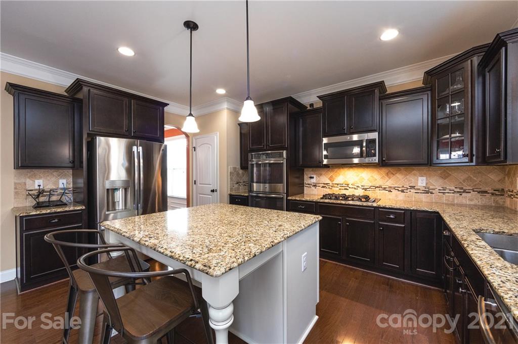 281 Annatto Way Tega Cay, SC 29708 - Photo 4 of 48 a kitchen with stainless steel appliances granite countertop table chairs sink refrigerator and microwave