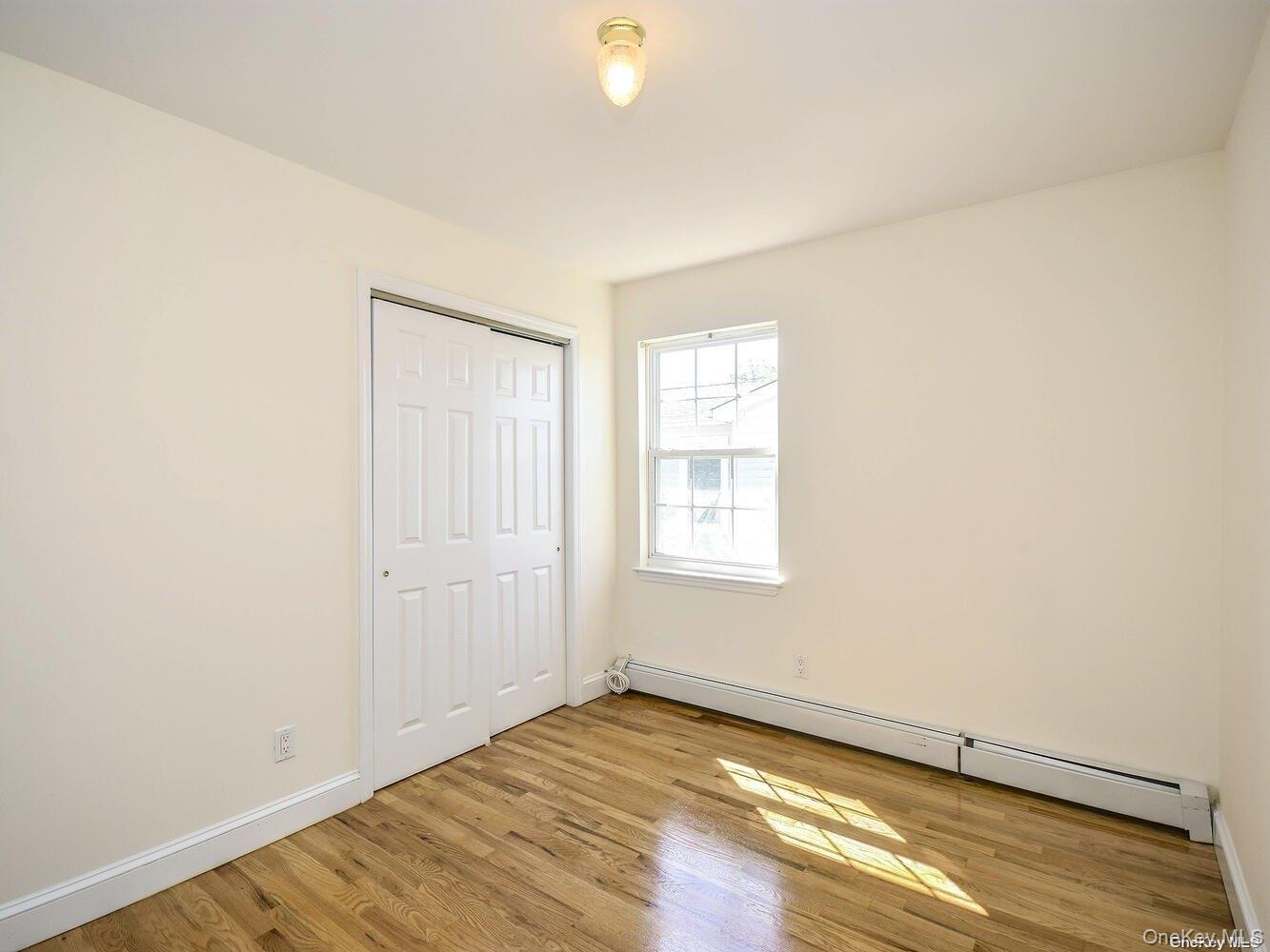34 Firwood Road, Unit B Port Washington, NY 11050 - Photo 16 of 25 an empty room with wooden floor and windows