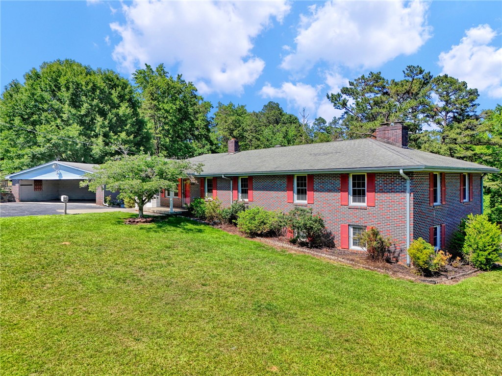 7876 Highway 11 Walhalla, SC 29691 - Photo 3 of 35 Mature trees frame this classic brick home, featuring a detached carport and manicured landscaping.