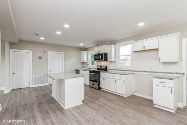 170-180 America Street Fall River, MA 02721 - Photo 10 of 40 a kitchen with stainless steel appliances granite countertop a stove top oven a sink dishwasher and a refrigerator with wooden floor