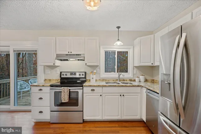 a kitchen with stainless steel appliances granite countertop a stove a sink and a refrigerator