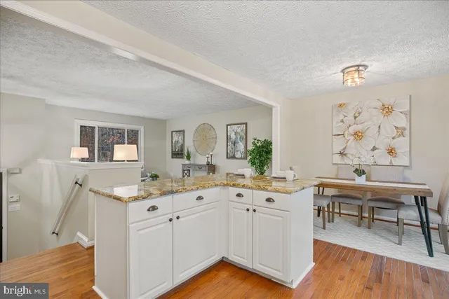 a view with cabinets a sink dishwasher and a dining table with wooden floor