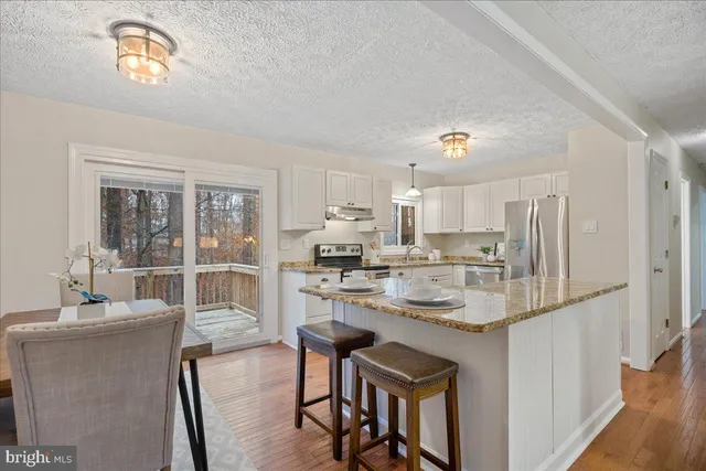 a kitchen with kitchen island a stove a table and chairs in it
