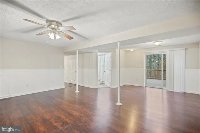 a view of an empty room with wooden floor and a ceiling fan