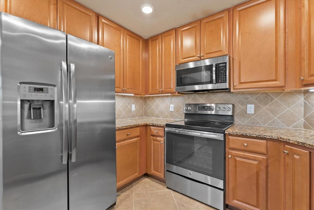 20080 Ragazza Circle, Unit 102 Venice, FL 34293 - Photo 22 of 49 a kitchen with granite countertop a refrigerator stove and microwave