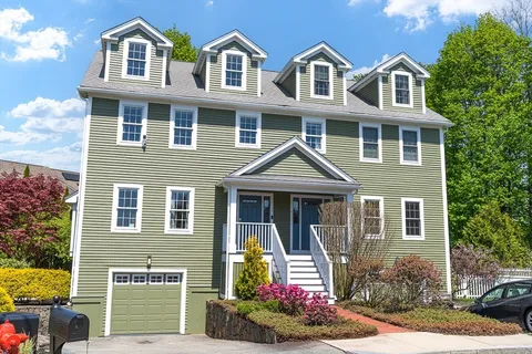 a front view of a house with a yard and potted plants