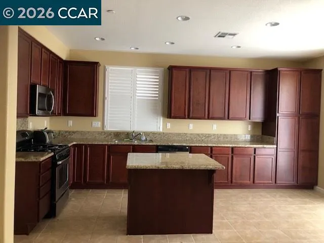 a kitchen with granite countertop stainless steel appliances a stove a sink a microwave and cabinets