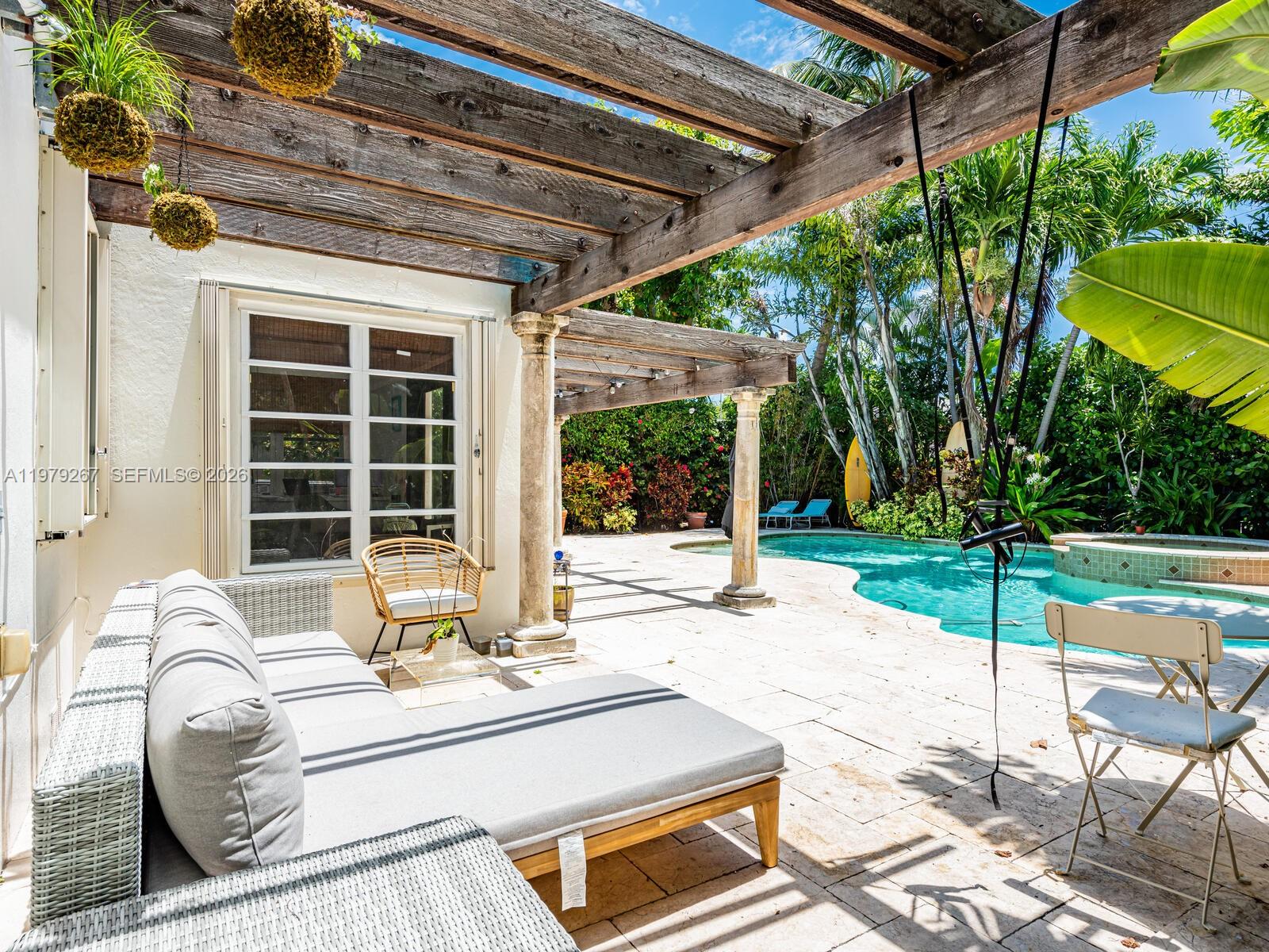 8927 Hawthorne Avenue Surfside, FL 33154 - Photo 2 of 40 a view of a patio with a table and chairs under an umbrella with a small yard